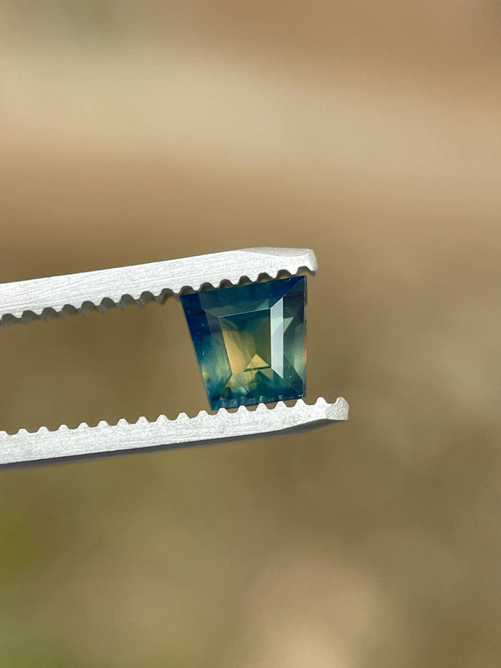 Australian sapphire in tapered baguette cut showing striking bi-color zoning of green and yellow with hints of blue