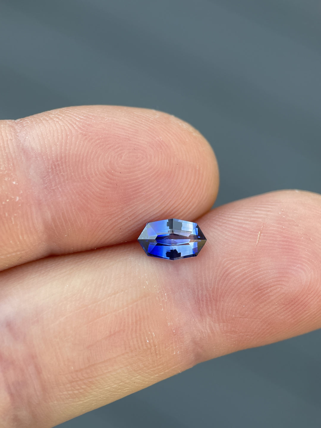 Vibrant 1.03 carat bi-color sapphire, showcased on a finger, features a custom geometric marquise cut, dimensions 8.30 x 5.10 x 3.30 mm, originating from Sri Lanka and treated with heat