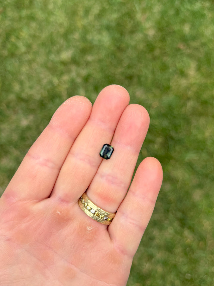 2.14 carat parti sapphire resting on a fingertip, highlighting the deep peacock and yellow hues.