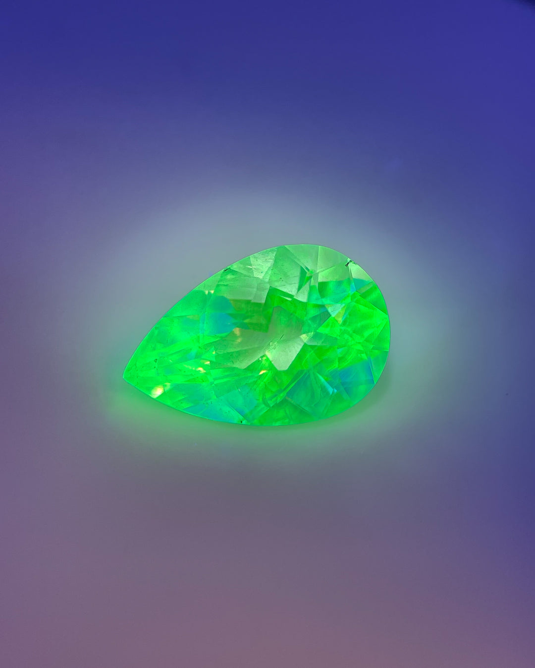 The same 2.30-carat hyalite opal glowing neon green under UV light, revealing its natural fluorescence.