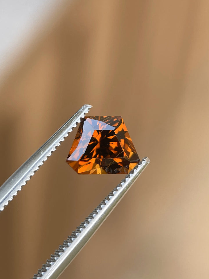 Detailed view of a Hessonite Garnet cut in a Custom Geometric Shield design, 2.00 carats, radiating yellow, orange, and brown tones, from Kenya.