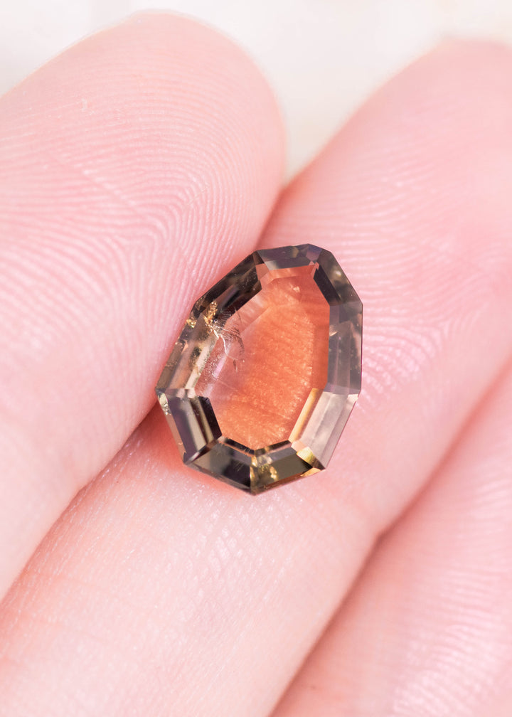 3.20CT pink, purple, and peach Tanzanite shown on fingertips for scale, highlighting the elongated shield portrait cut and natural color blend from Merelani Hills, Tanzania