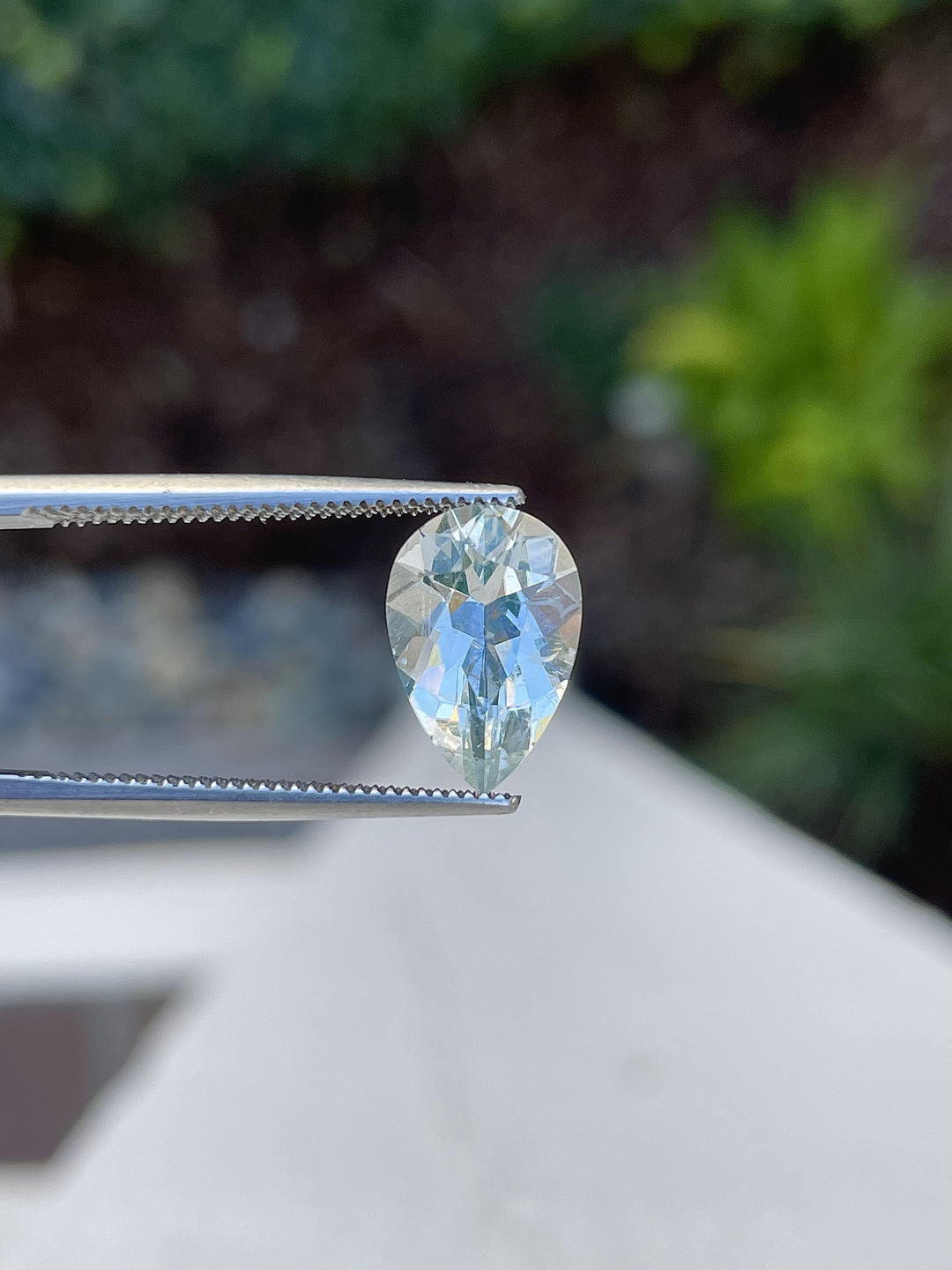 A natural 2.30-carat hyalite opal from Mexico held in tweezers, highlighting its brilliance and transparency.