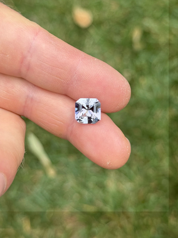 Hand shot of 4.59ct fancy Tanzanite showing a mix of pastel lavender and deep pink-green flashes