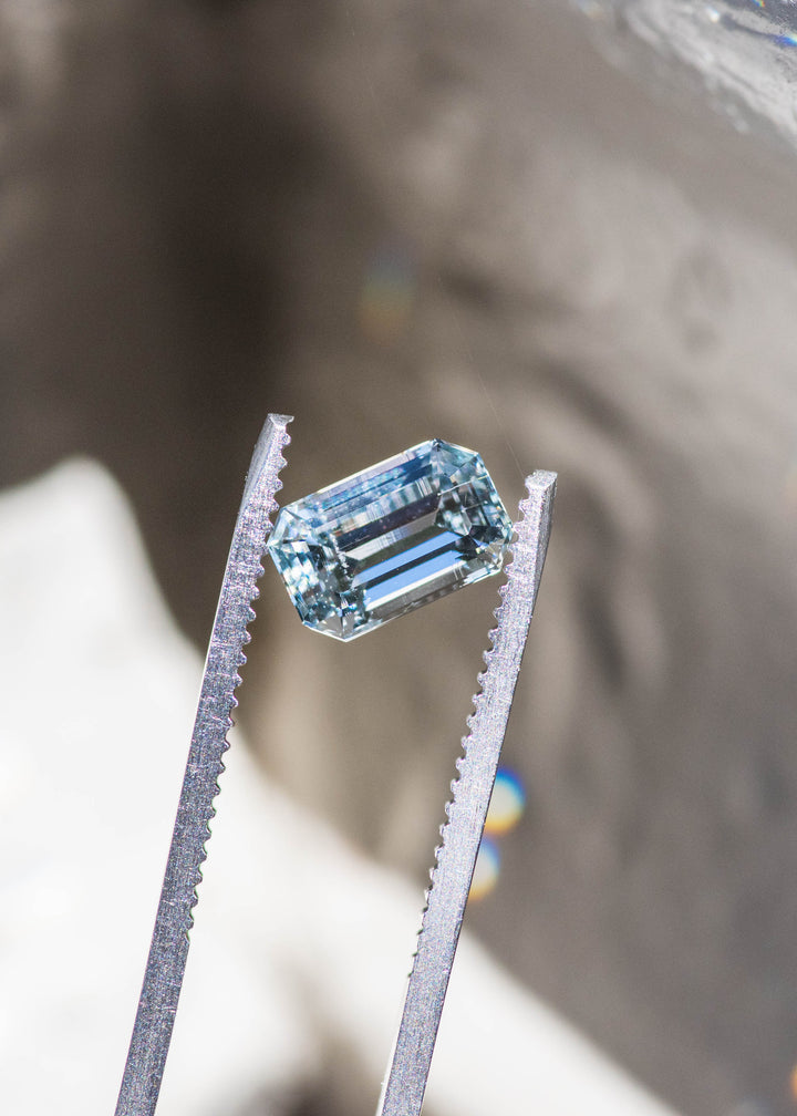 Close-up of a 1.63 carat untreated Colorado aquamarine showing its custom emerald cut, crisp step facets, and pale blue color.
