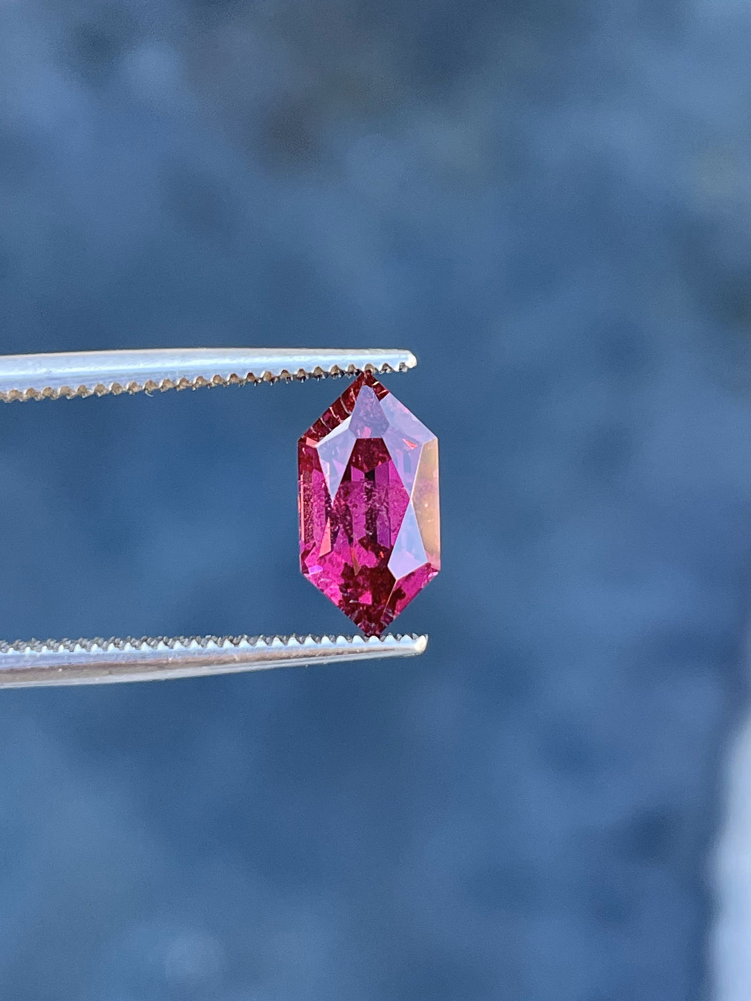 Detailed view of a Kenyan garnet weighing 2.40 carats, showcasing its unique hexagon shape, red-purple color, and untreated brilliance.