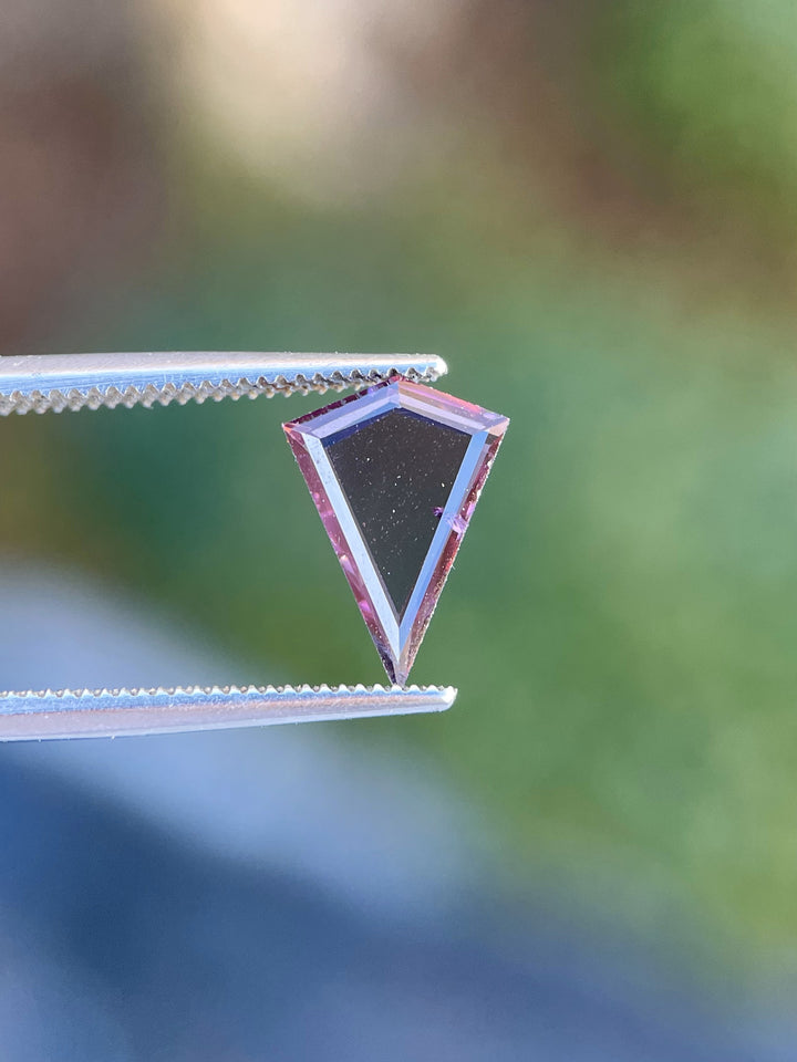 1.44 carat spinel gemstone with a custom kite step cut, showcasing vibrant purple and pink tones, untreated and of Sri Lankan origin.