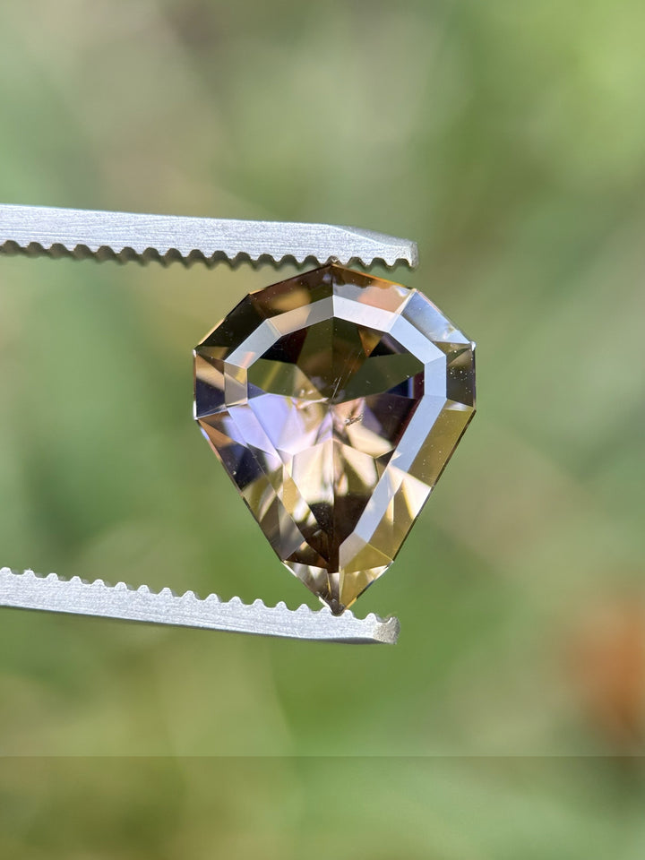 Untreated Tanzanite 3.74ct shield cut in tweezer shot, showcasing rich red and peach colors from Merelani Hills