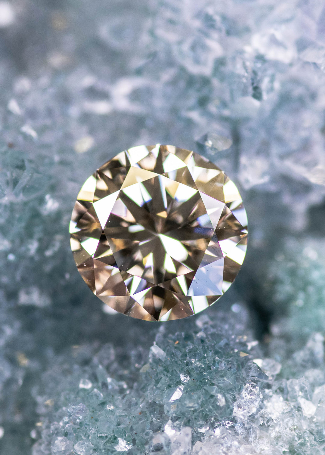 2.40ct C3 champagne round brilliant diamond displayed on crystal surface, showing warm golden-brown sparkle.