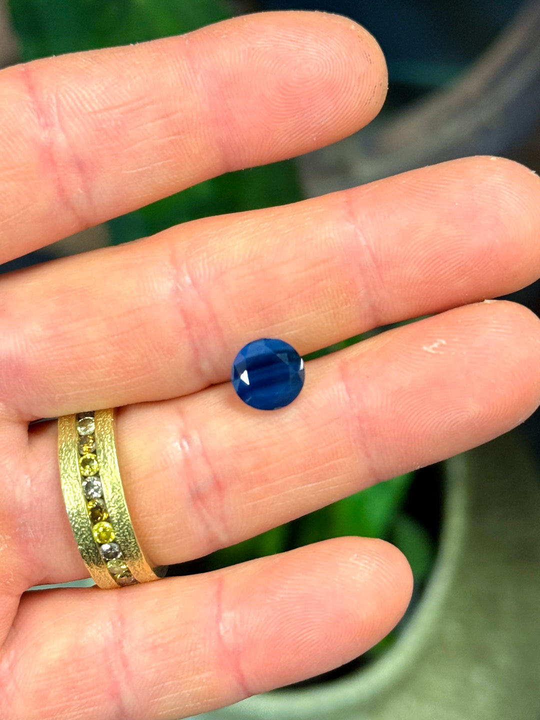 Hand holding a blue gemstone with a blurred background