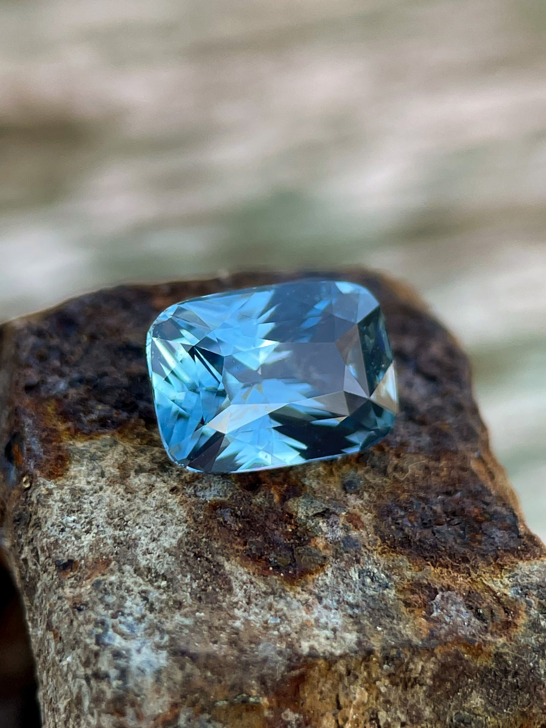 A 1.52-carat denim blue and green sapphire resting on a rustic surface, highlighting its heated treatment and exceptional color play.