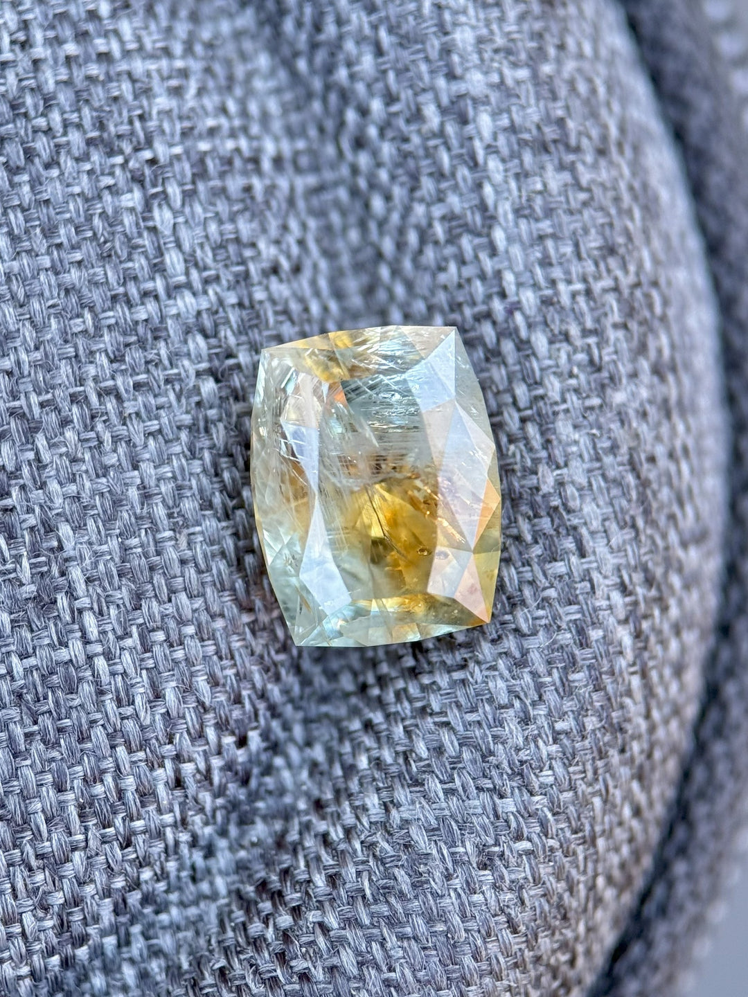 2.99ct sapphire from El Dorado Bar Deposit, Montana, placed on fabric to reveal untreated orange and teal color zoning in a custom cushion cut
