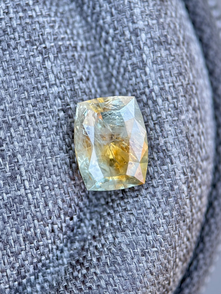 2.99ct sapphire from El Dorado Bar Deposit, Montana, placed on fabric to reveal untreated orange and teal color zoning in a custom cushion cut