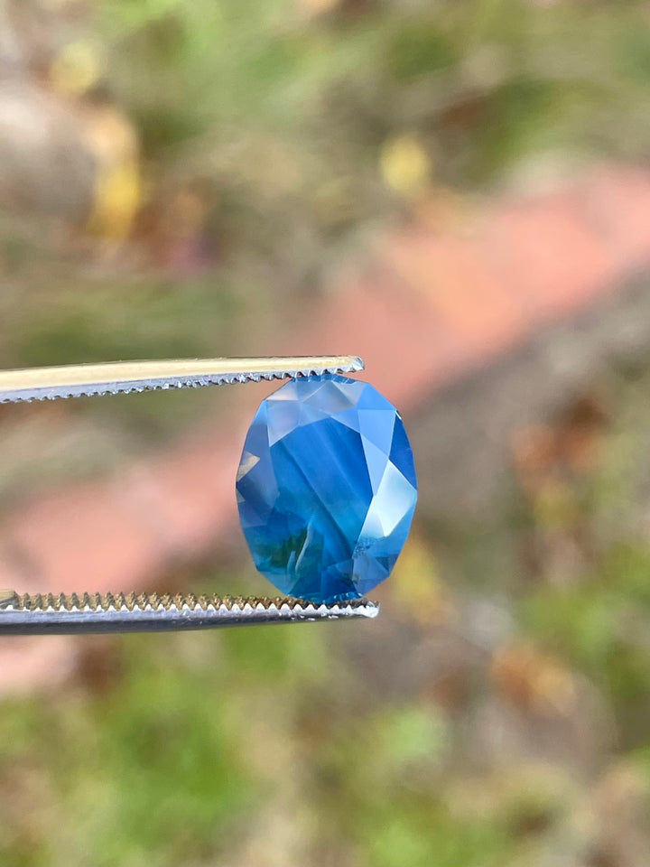 Elegant 5.23 carat sapphire, oval cut, showcasing deep blueberry, green, and teal tones, unheated, from Gombe, Nigeria.