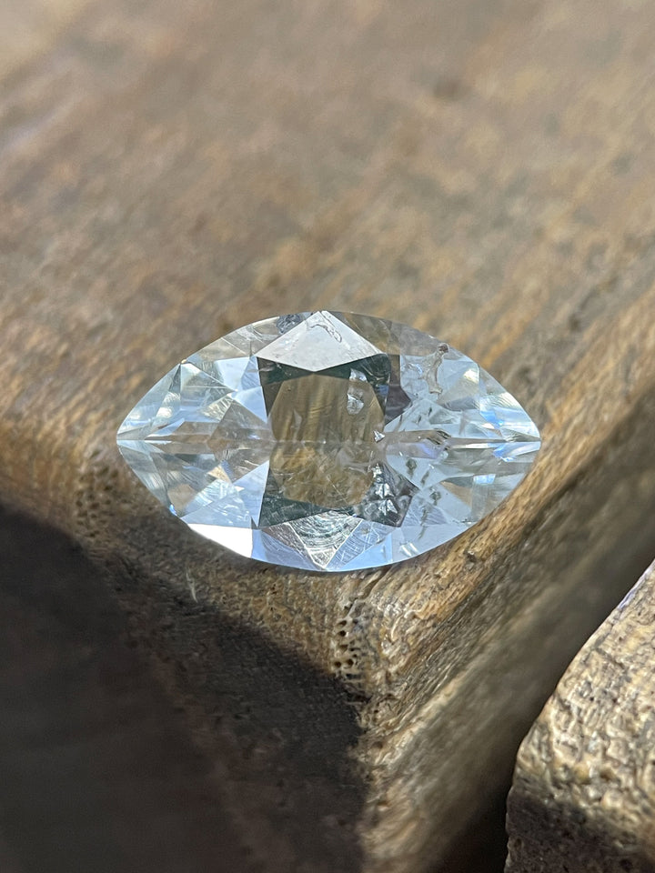 A beautiful oval-cut Hyalite Opal resting on a wooden surface, displaying its natural transparency and brilliance.