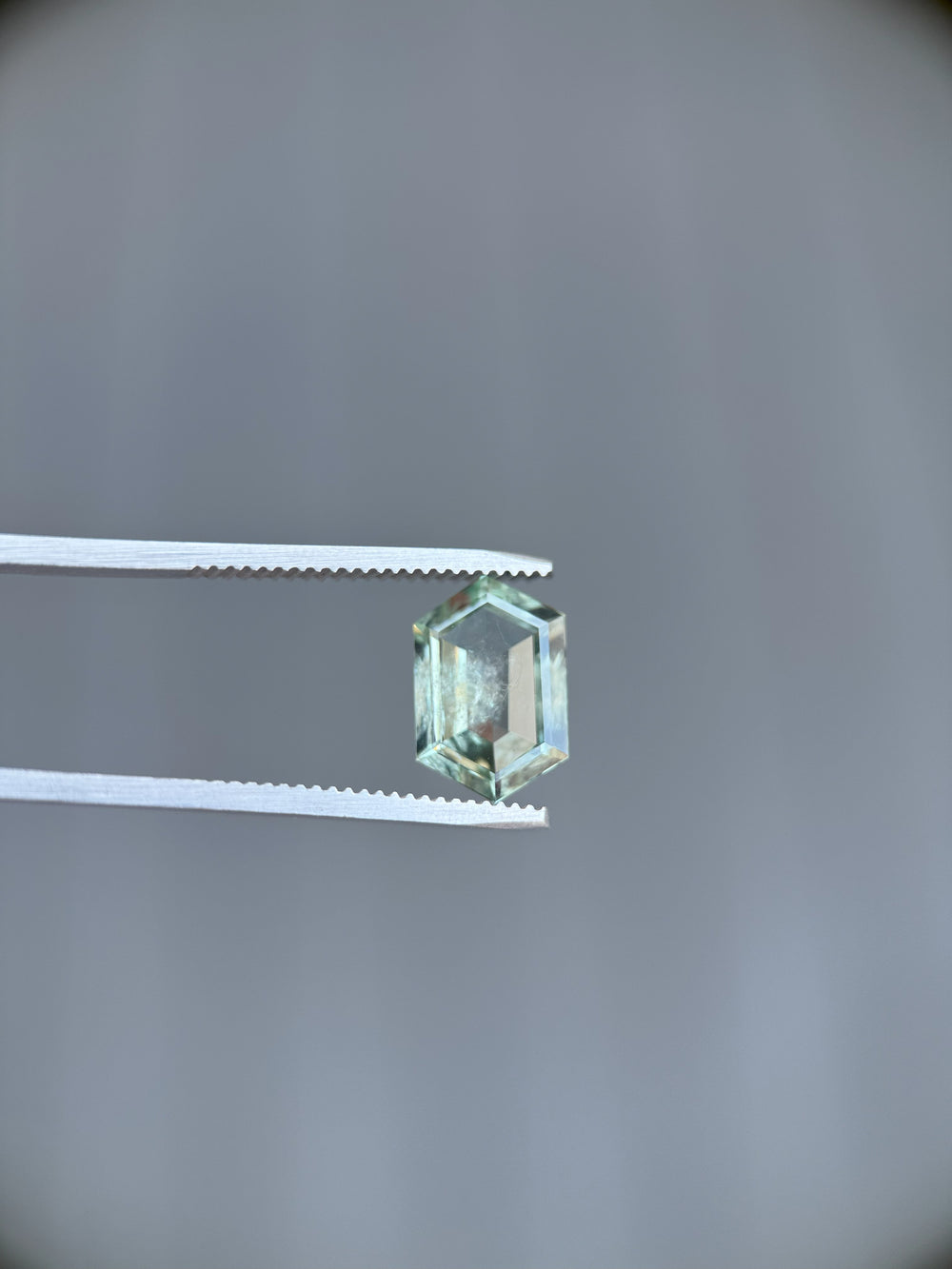 Montana-origin 3.80ct sapphire in geometric hexagon step cut held by gem tweezers, showcasing teal and green tones