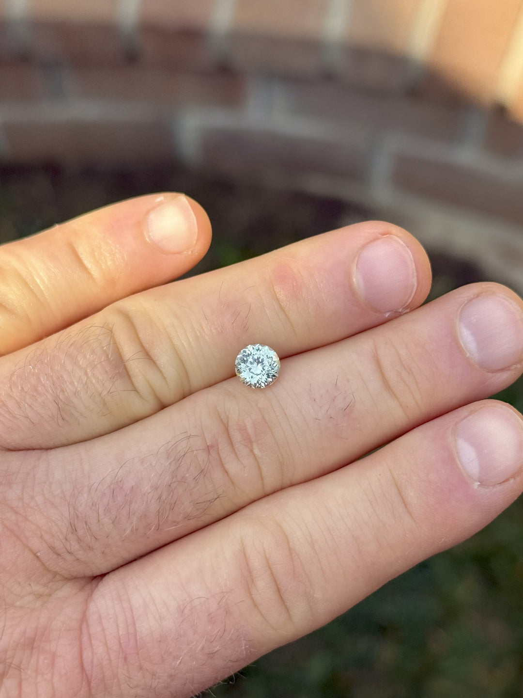 Round Portuguese cut sapphire in earthy mint green from El Dorado Bar, Montana – displayed on hand outdoors