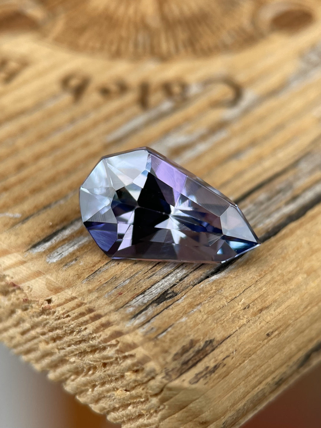 A 3.31-carat tanzanite gemstone displaying a captivating blend of gray, blue, and purple hues, skillfully cut into a modified geometric pear shape, sourced from Merelani Hills, Tanzania.