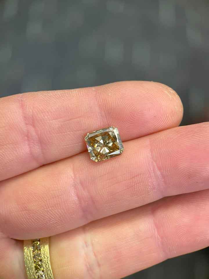 A 3.68-carat radiant cut champagne diamond with a natural fancy brown-yellow hue, showcasing its brilliance on a hand. Ethically sourced from the Argyle Mines, Australia.
