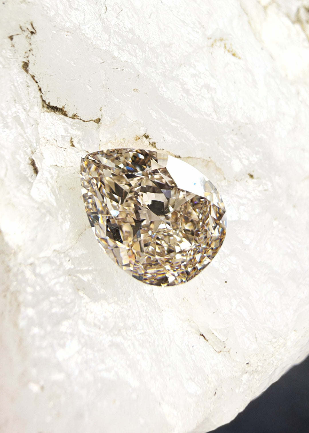 Fancy Pinkish Brown pear cut diamond with a rounded end, tapered point and warm brown coloration with pinkish undertones.