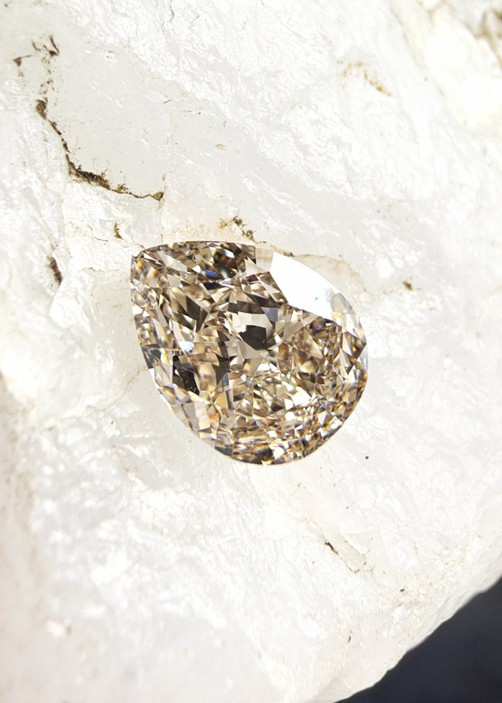 Fancy Pinkish Brown pear cut diamond with a rounded end, tapered point and warm brown coloration with pinkish undertones.