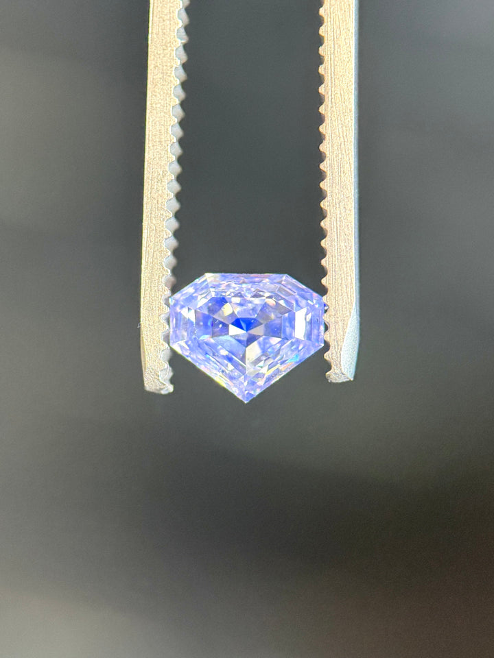 Fluorescence view of a 1.01 carat E color SI1 clarity diamond under UV light, glowing vivid blue. The shield step cut diamond from Gahcho Kué, Canada, demonstrates natural fluorescence and brilliance.