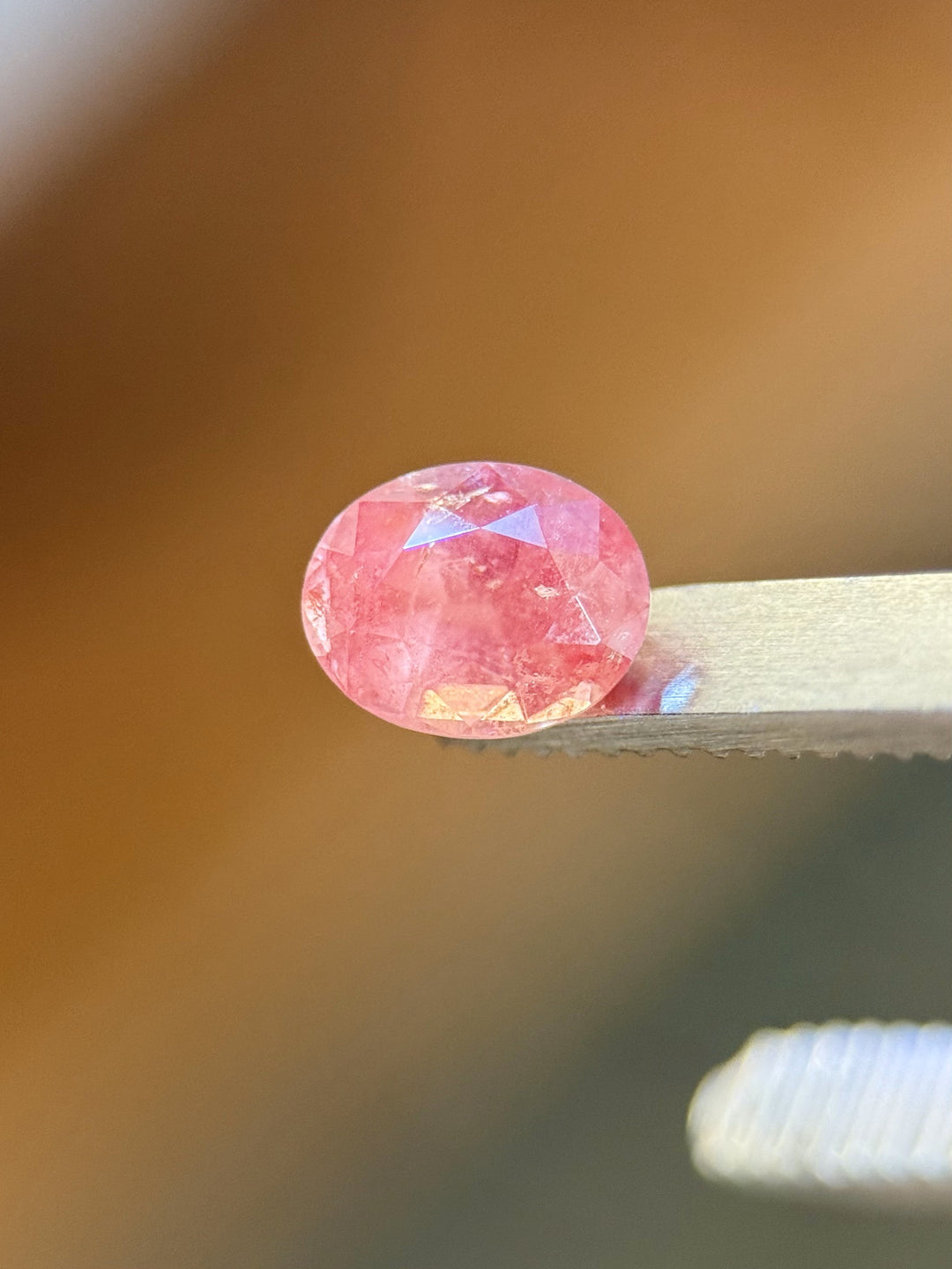 Side view of untreated 1.37 carat sapphire in mauve pink tones, resting on a metal surface