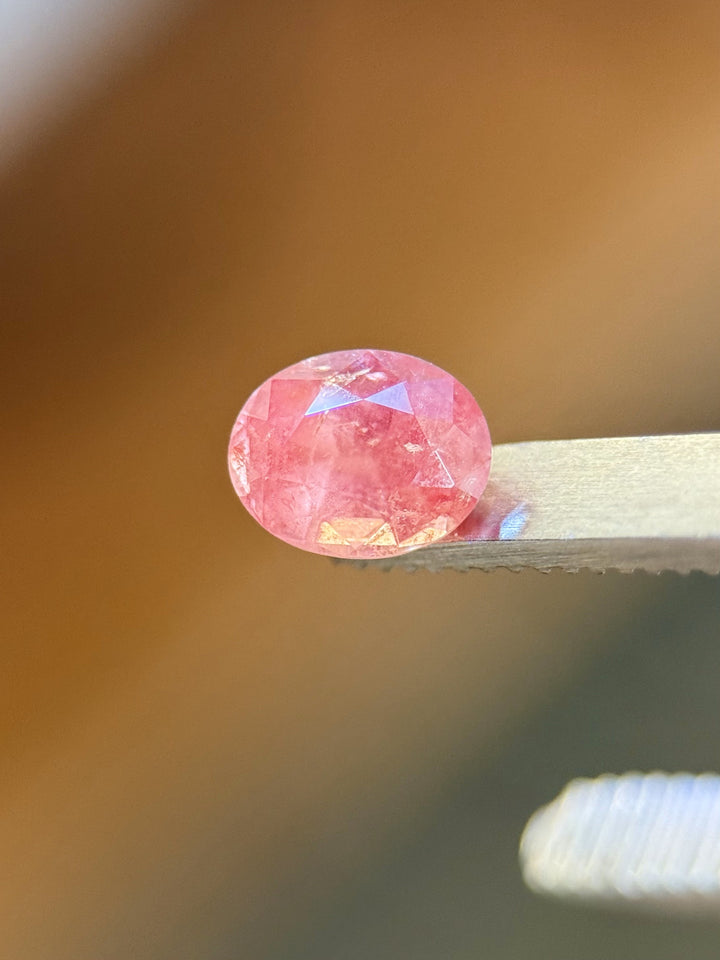 Side view of untreated 1.37 carat sapphire in mauve pink tones, resting on a metal surface