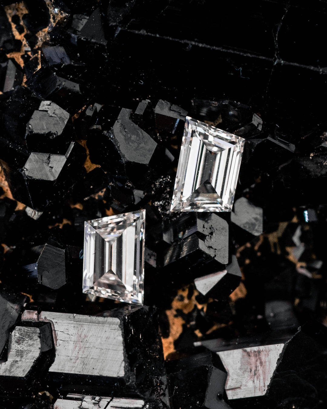0.37 carat G color VVS-VS trapezoid step cut diamond pair displayed on a black crystal mineral matrix, highlighting the step-cut geometry, brilliance, and natural sparkle of untreated South African diamonds.
