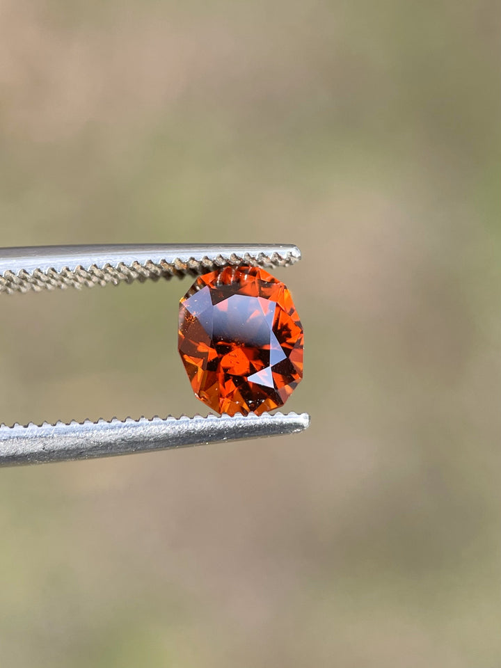 Natural 1.68-carat Hessonite Garnet with fiery red-orange tones, expertly cut in a geometric brilliant oval shape.