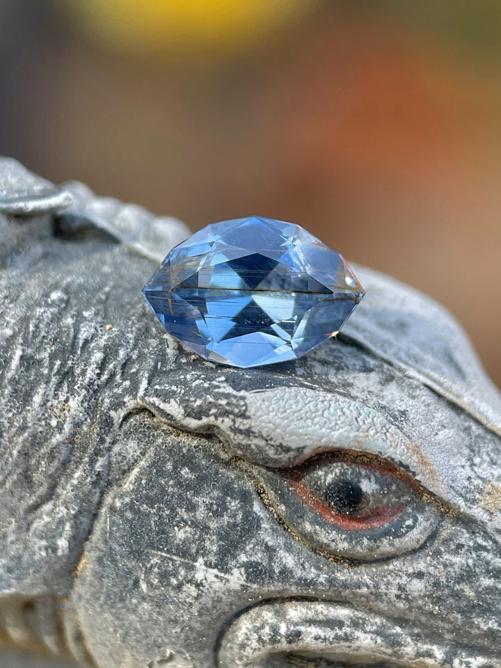 1.36ct blue and periwinkle marquise sapphire from Umba River resting on a carved stone surface, highlighting its brilliance and clarity.