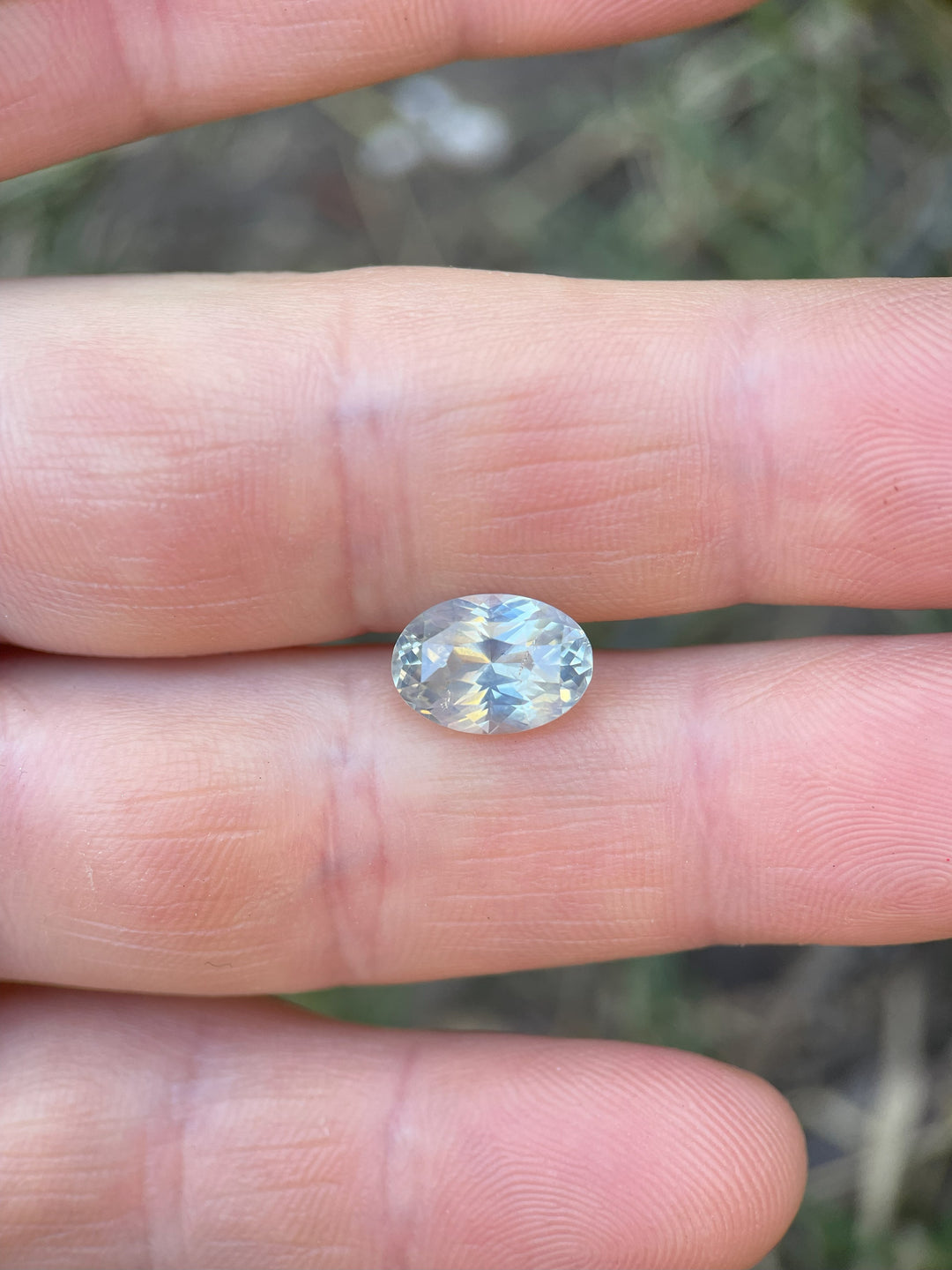 A 4.23-carat opalescent white sapphire with yellow undertones, displayed on a hand to highlight its size and brilliance.