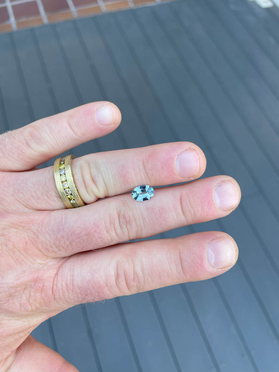 1.61-carat seafoam blue sapphire, oval cut, displayed on fingers for scale, ethically sourced from Sri Lanka.