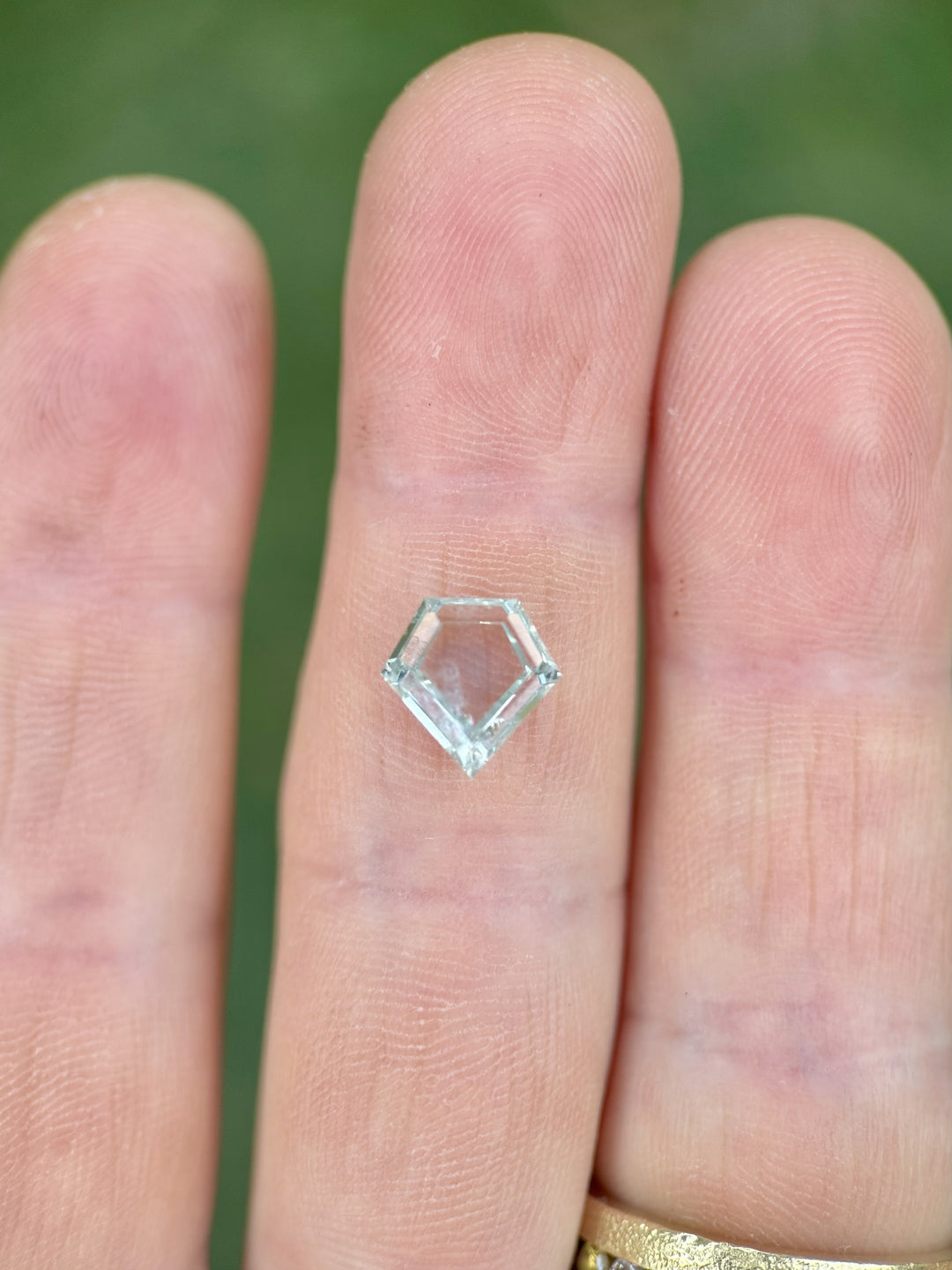 Custom shield cut Montana sapphire in heated mint and green tones, 2.81 carats, displayed on neutral surface