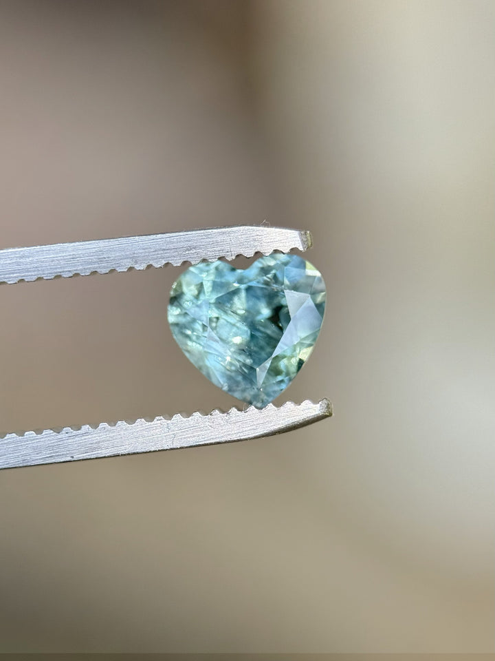 Macro view of heart cut teal sapphire held in tweezers – 1.71ct precision mixed cut from El Dorado Bar.