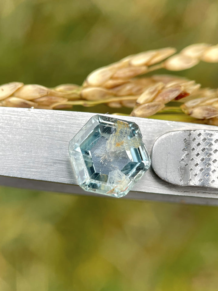 Montana-origin teal green sapphire, displayed on a textured surface, highlighting its hexagonal shape and 4.00 carat weight.