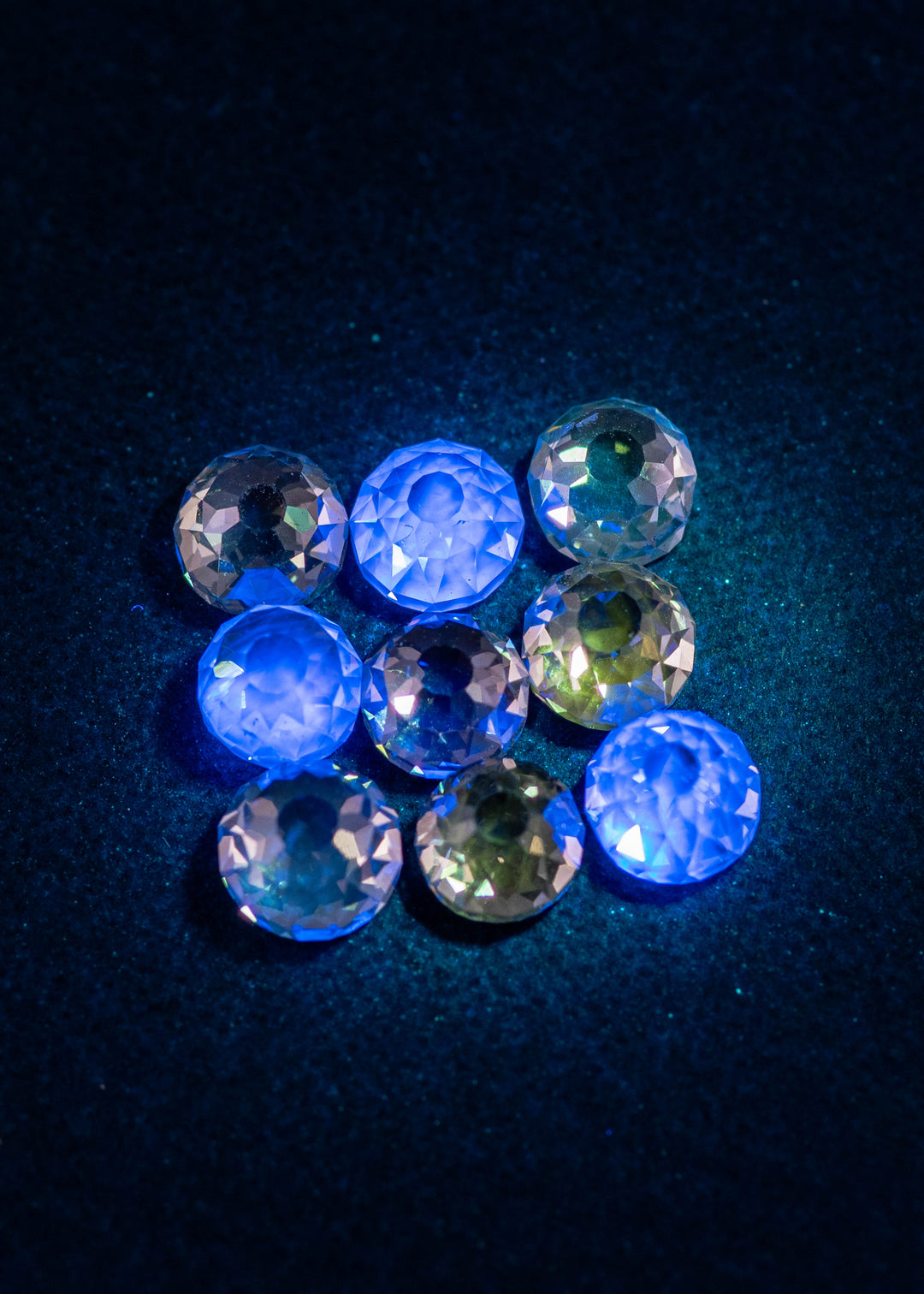 Mughal cut fancy light brown diamonds under UV light showing light blue fluorescence, highlighting antique faceting, open culets, and VVS clarity in a nine-piece diamond parcel