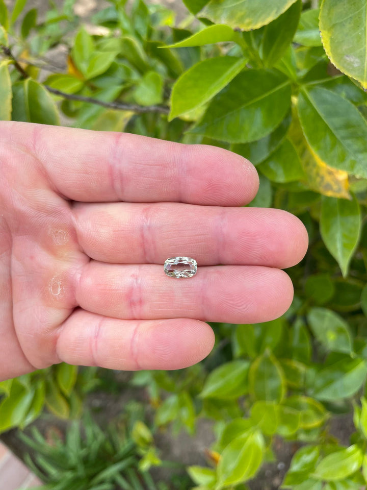 A radiant 2.29-carat sapphire rests in the palm, showcasing vibrant yellow, teal, and green hues, shaped in a modified cushion cut, sourced from the Umba River in Tanzania, untreated.