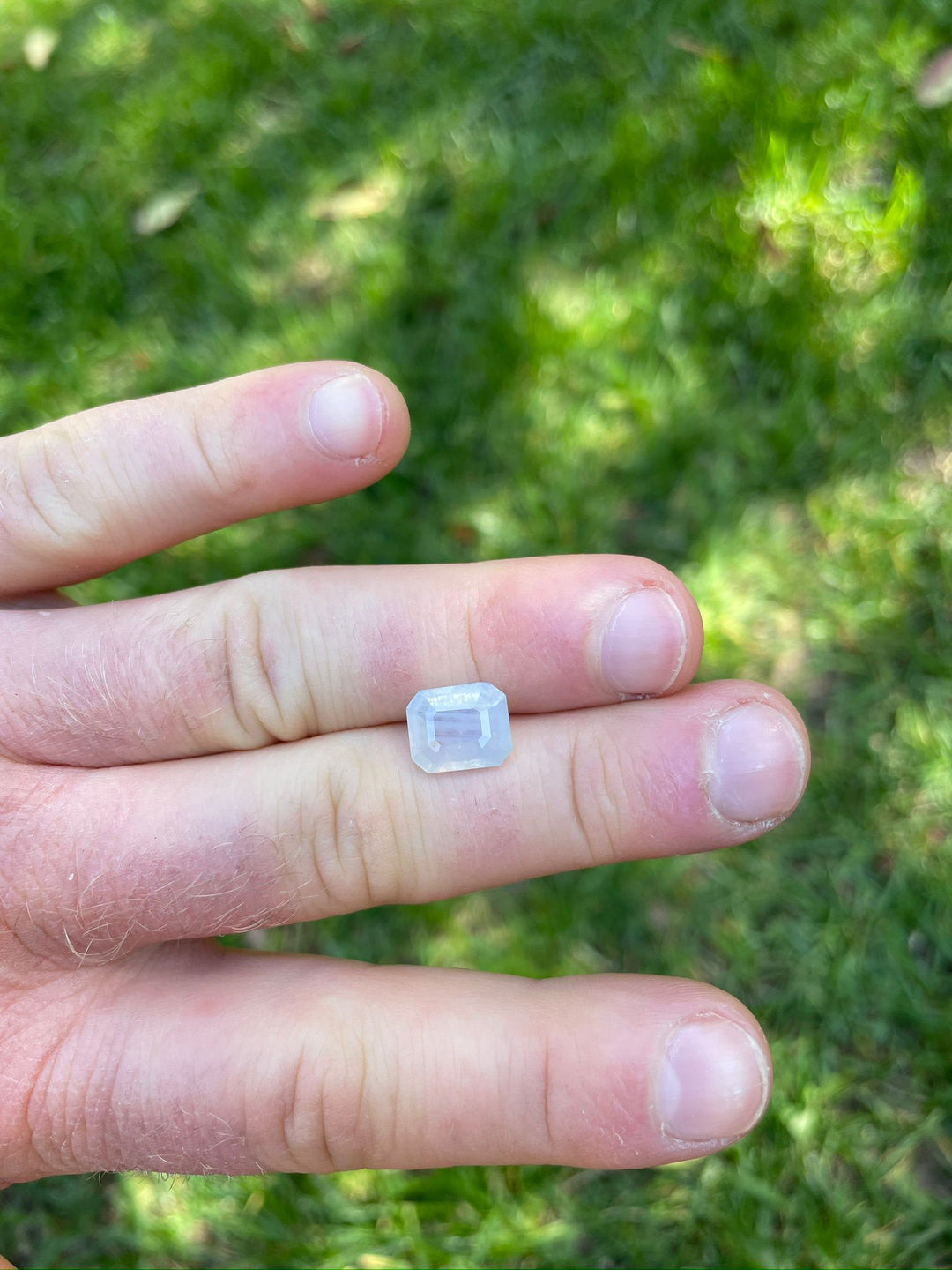 5.10-carat Sri Lankan sapphire in a person's hand, displaying an elegant octagonal step cut and a soft opalescent color with periwinkle nuances, valued at $3825.