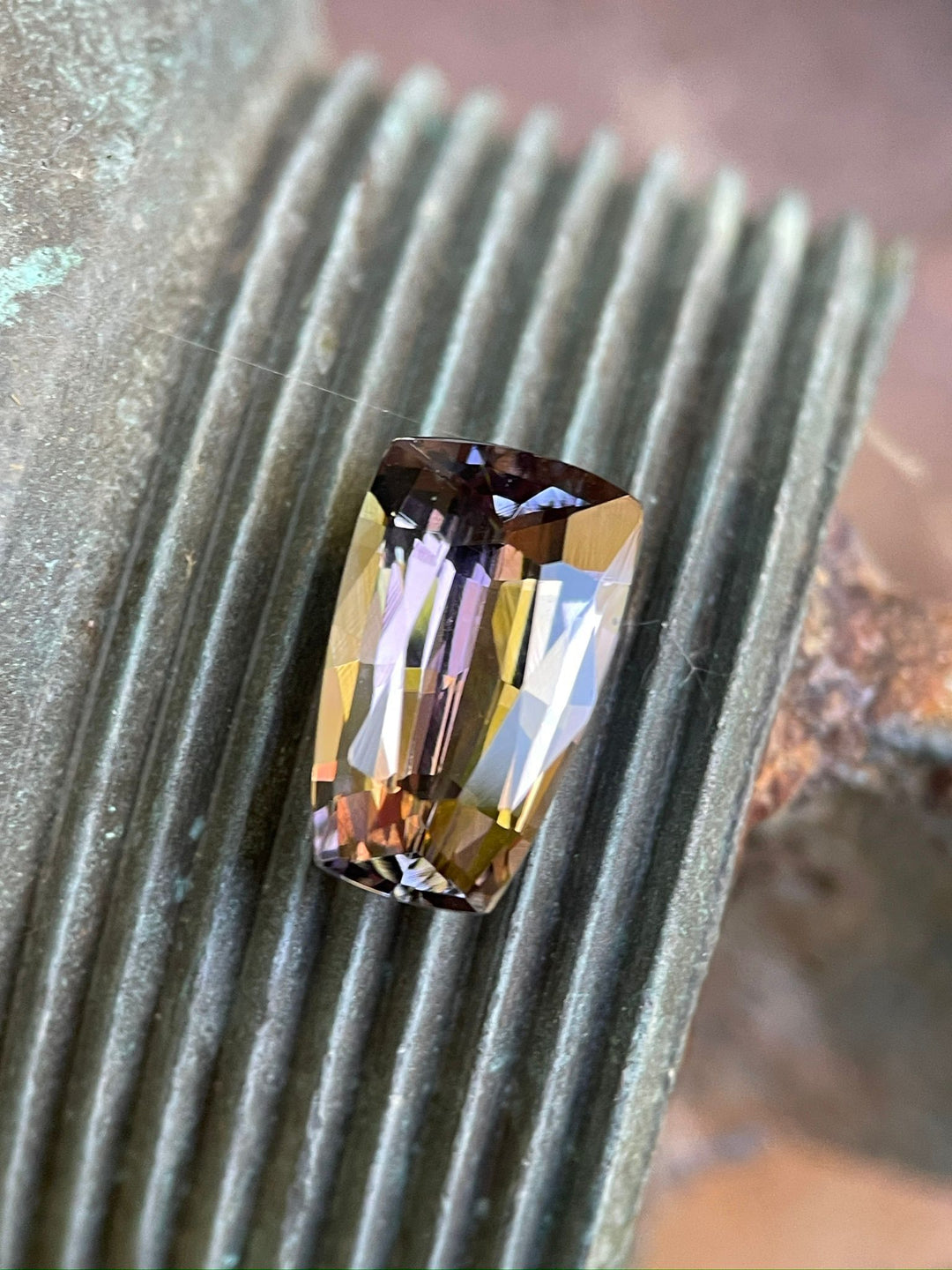 4.98-carat Tanzanite gemstone with a unique tapered shield mix cut showcased on ridged metal, highlighting its deep purple to champagne hues, from the Merelani Hills, Tanzania.