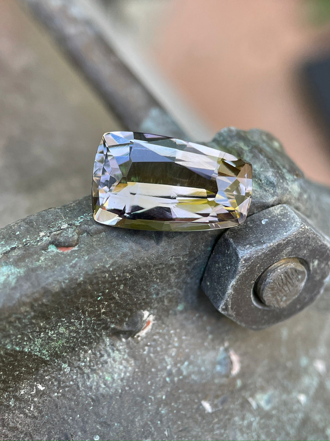 Exquisite 4.98-carat Tanzanite with a custom tapered shield mix cut, resting on a mossy rock, displaying rich purple and champagne colors, sourced from the Merelani Hills, Tanzania.