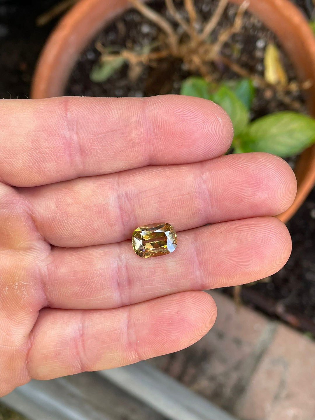 Stunning 3.51-carat modern antique cushion cut diamond held in a person's hand, displaying a natural fancy brown-yellow color, VS1 clarity, from Lesotho, South Africa.