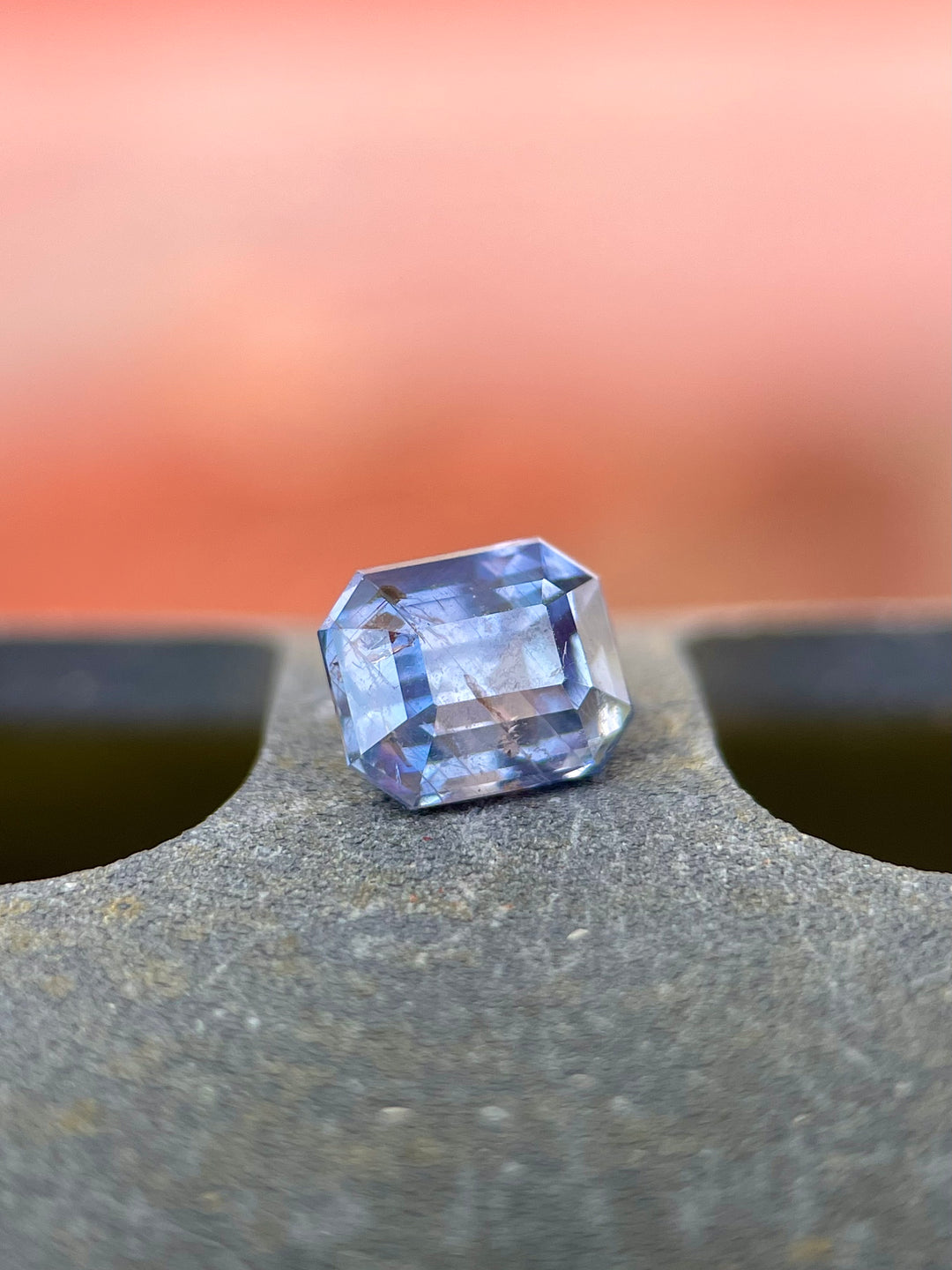 Exquisite 1.81-carat bi-color sapphire with shades of lavender and blue, expertly cut in an emerald shape. Displayed against a subtle background that highlights its clarity and natural hues, this gemstone from the Umba River, Tanzania, demonstrates its superior quality and untreated beauty.