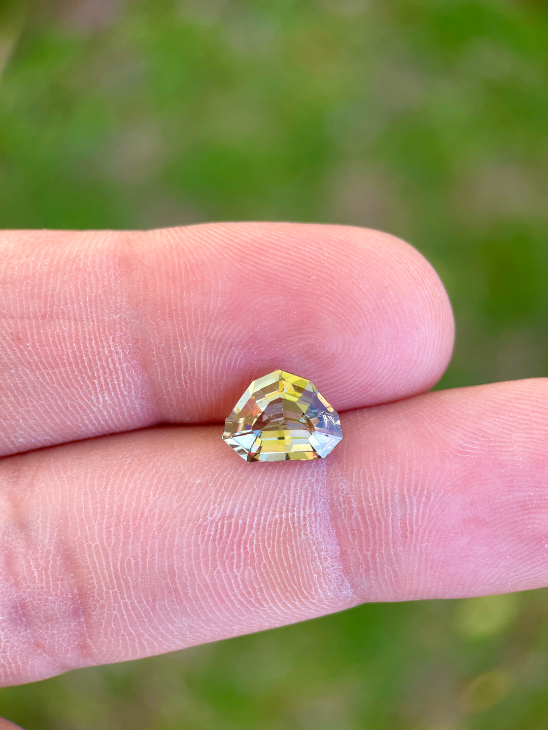 Close-up view of a 2.99 carat custom shield step cut Tanzanite, featuring a blend of slightly teal, peach, and yellow hues, untreated and originating from Merelani Hills, Arusha Region, Tanzania.