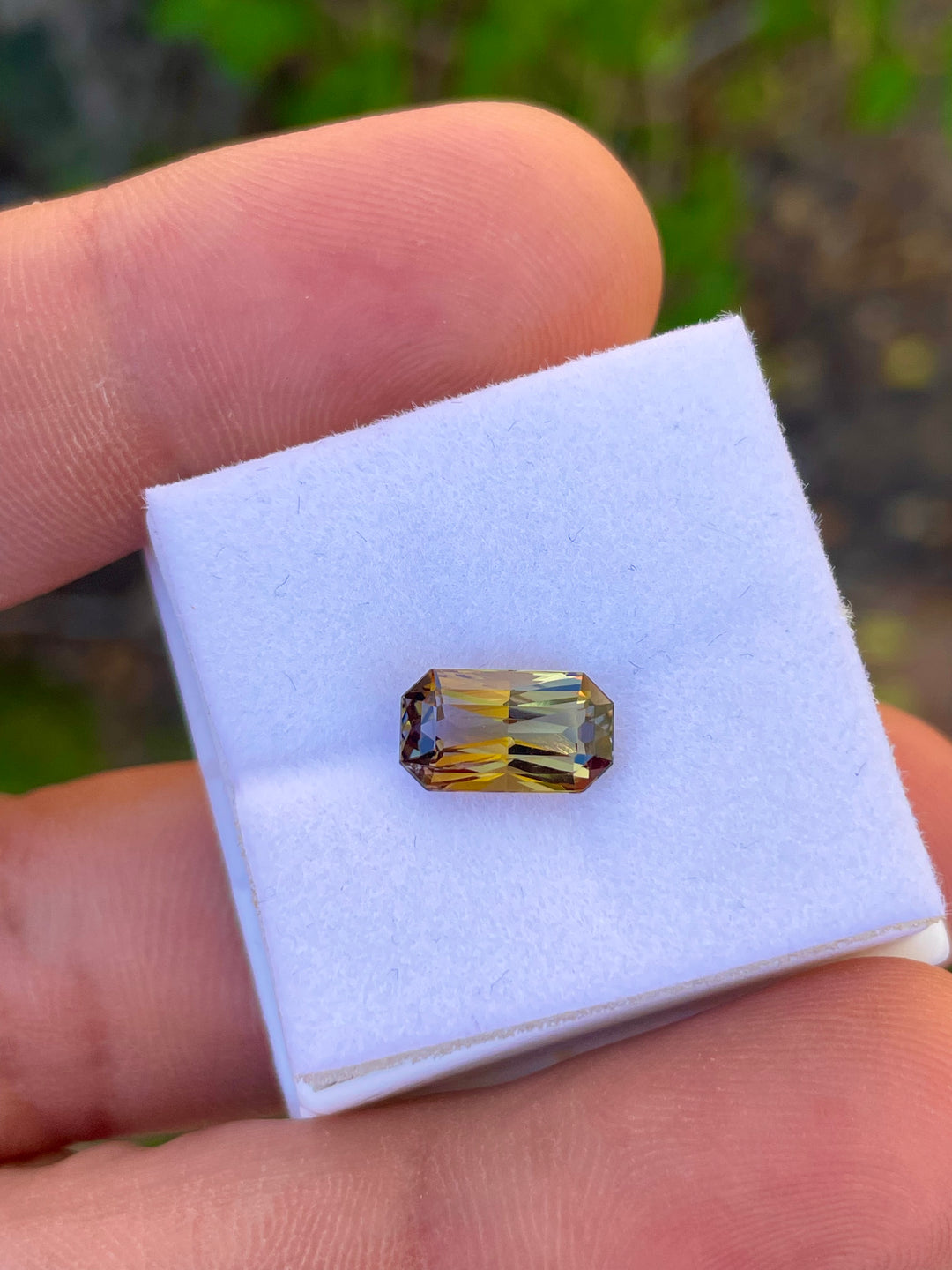 Detailed Image of a Custom Elongated Radiant Cut Tanzanite Gemstone in Greenish Golden, Peach, and Yellow Colors, Weighing 2.30 Carats, with Dimensions 10.59 x 6.05 x 4.43 mm, from Merelani Hills, Arusha Region, Tanzania - No Treatment