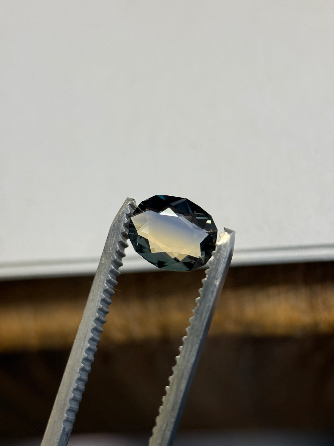 Close-up of blue and yellow Madagascar parti sapphire highlighting clean facet junctions, saturated navy-blue upper facets, and warm golden tones reflecting through the pavilion.
