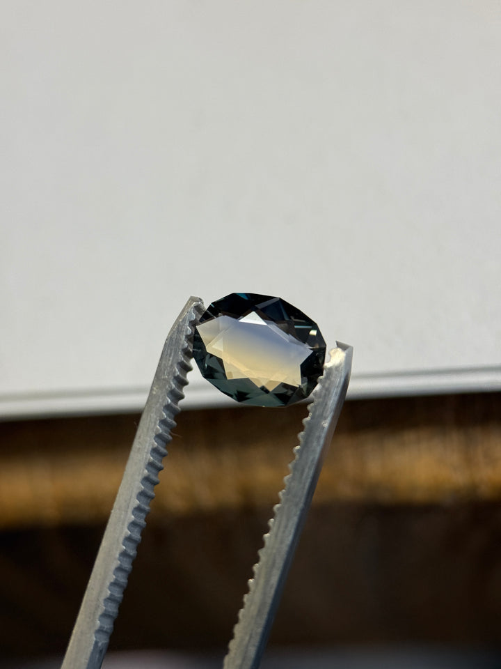Close-up of blue and yellow Madagascar parti sapphire highlighting clean facet junctions, saturated navy-blue upper facets, and warm golden tones reflecting through the pavilion.