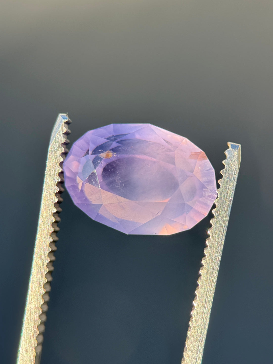 Close-up of opalescent purple sapphire showing internal silk and soft light diffusion.