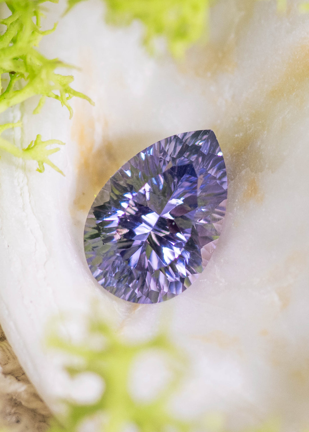 Loose lavender pink purple sapphire from Sakaraha Madagascar resting on natural stone showing the custom concave pear cut and pastel color tones.