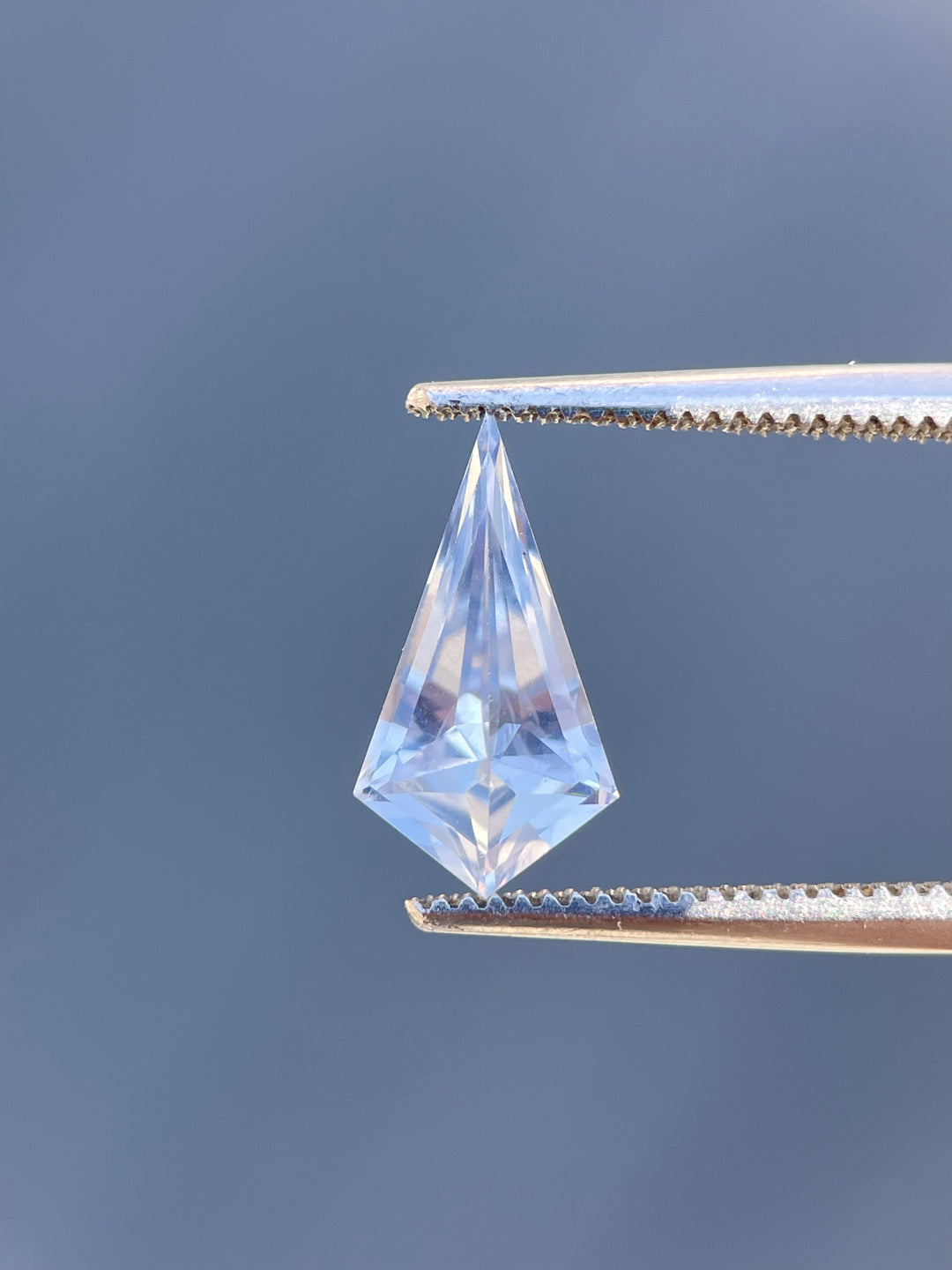 Vivid display of a 1.66 carat periwinkle and powder blue sapphire, with geometric step cut, placed on a reflective surface to enhance its natural brilliance, sourced from Sri Lanka.